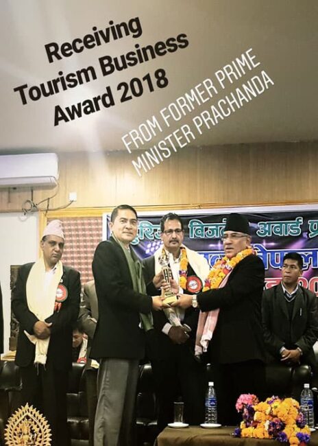 Tilak proudly accepting the Tourism Business Award 2018, presented by former Prime Minister Puspa Kamal Dahal 'Prachanda', exemplifying recognition of excellence in the Nepalese tourism sector